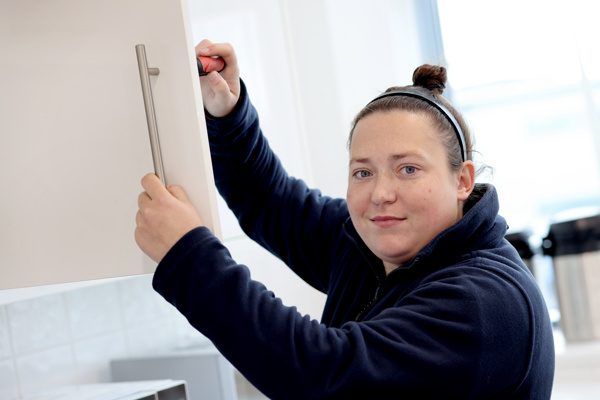 A woman fixing a cupboard.
