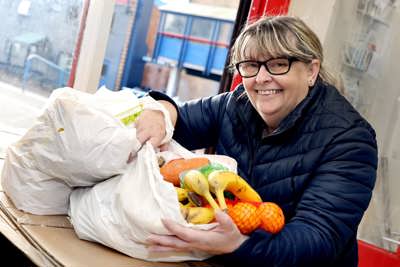 A woman with glasses sitting next to two bags of groceries